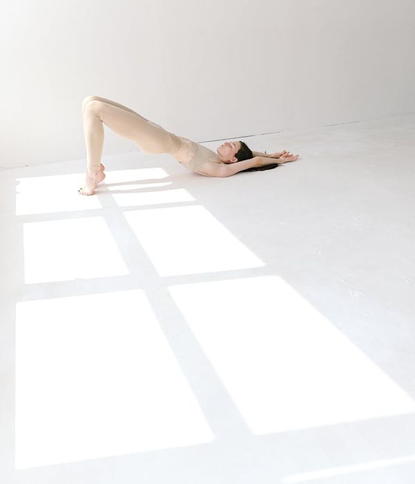 Woman practicing a peaceful yoga pose in a bright, calm studio.